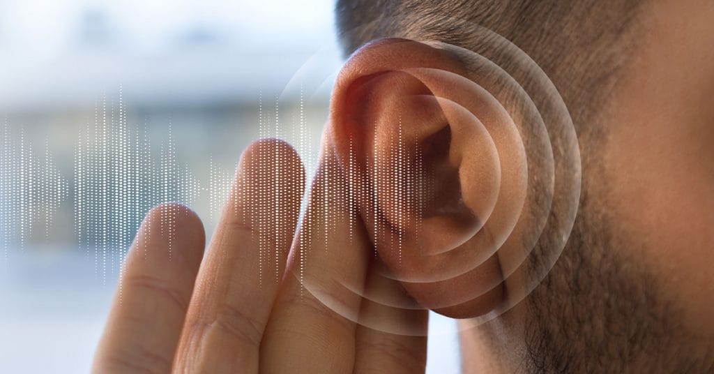 Imagem de um ouvido humano em close-up, com ondas sonoras digitais ilustradas ao redor, representando percepção auditiva ou captação de sons sutis