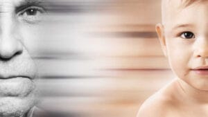 Metade do rosto de um homem idoso em preto e branco ao lado da metade do rosto de um bebê colorido, com efeito de transição suave entre as imagens.